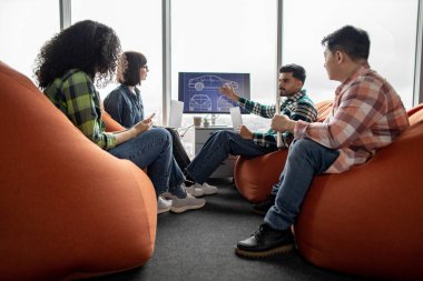 Profesyonellerden oluşan çeşitli takımlar, yumuşak nonoşlarla iş birliği yapmakla meşgulken akıllı aletlerden faydalanıyorlar. Günlük giysiler içindeki otomotiv mühendisleri ofiste sergilenen dijital verileri analiz ediyorlar.