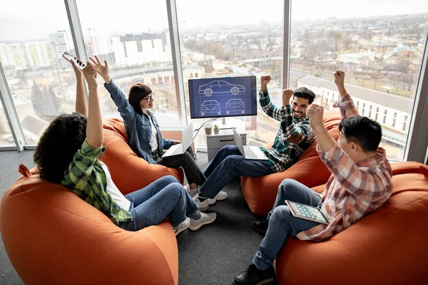 Empresários Multirraciais Excitados Levantando Mãos Alegremente Enquanto Sentam Com Laptops — Fotografia de Stock