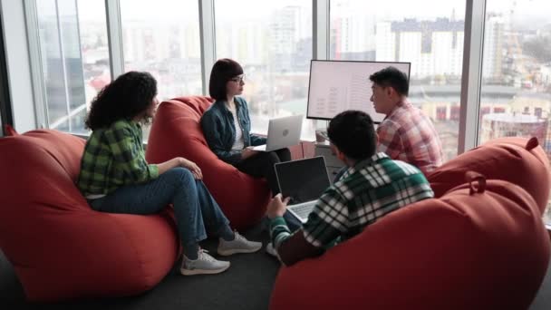 さまざまな男性と女性の同僚が設計図を提示し 他のチームメイトはオフィスのノートパソコンでメモを取ります 対話型ディスプレイ上の構造物を構築する際に安全上の脅威を見つけるプロジェクトマネージャ — ストック動画