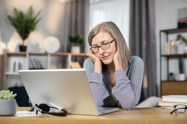 Yorgun, orta yaşlı, gözlüklü bir kadın uzak bir ofiste bütün gün çalıştıktan sonra dizüstü bilgisayar ekranına bakarken yorgun hissediyor. Üst düzey bayan online beyin fırtınası sonrası yorgunluktan ölüyor..