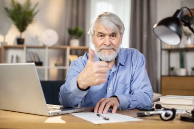 Yetişkin, kendinden emin, beyaz bir adam evden uzakta taşınabilir bilgisayar kullanırken not alıyor.