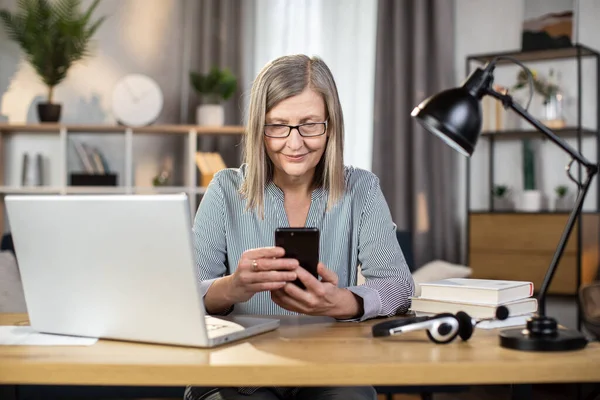 Mindful Senior Woman Spectacles Looking Phone Screen While Operating Modern — Stock Photo, Image