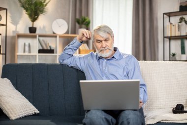 Diz üstü bilgisayarı olan, sıradan giyinmiş, düşünceli, olgun bir adam içeride keyifli bir meşgaleyle meşgul oluyor. 65 yaşlarında odaklanmış beyaz adam evdeki internet bağlantısıyla online macera filmi izliyor..