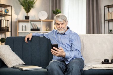 Diz üstü bilgisayarı olan, sıradan giyinmiş, düşünceli, olgun bir adam içeride keyifli bir meşgaleyle meşgul oluyor. 65 yaşlarında odaklanmış beyaz adam evdeki internet bağlantısıyla online macera filmi izliyor..