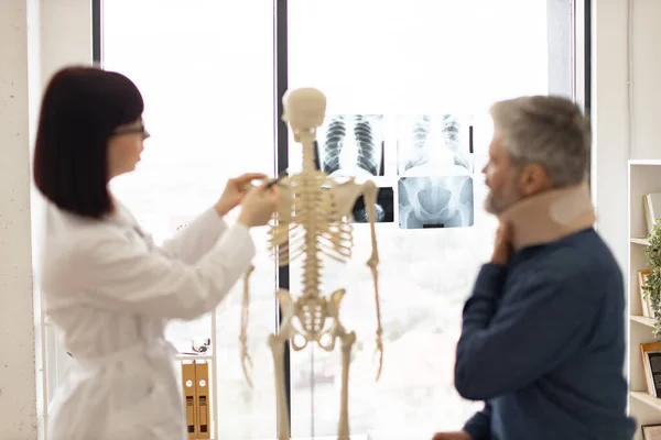 stock image Focus on detailed x-ray pictures of human chest and pelvic bones placed on window panel with adult people talking on blur foreground. Medical imaging test creating radiographs for initial diagnosis.