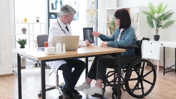 의사들의 신뢰할 성인은 안경을 미녀가 휠체어에 병원에서 책상을 작성하는 타블렛을 — 비디오