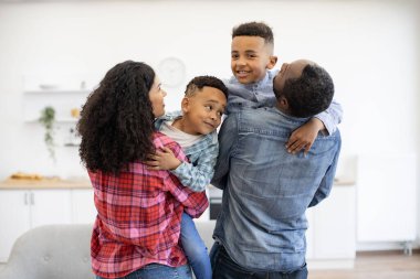 Anaokulu çocuklarını kollarında tutan çok kültürlü eşlerin masa oyunlarına ara vermeleri. Güneşli bir günde sıcak evden ayrılmadan önce arkadaşça bir aile yemeği planlama yürüyüşü..