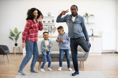 Modern dairenin parlak oturma odasında dinamik, etnik çeşitlilikte dört kişilik bir aile dans partisi veriyor. Kot giyen sağlıklı genç ebeveynler oğullarına boş zamanlarında değişik hareketler öğretiyor..