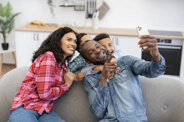 Família Multicultural Positiva Quatro Pessoas Usando Smartphone Moderno Enquanto Descansa — Fotografia de Stock
