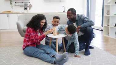 Dört kişilik aile, oturma odasındaki küçük masada tahta bloklarla masa oyunu oynuyor. Mutlu insanlar, sevgi ve özenin önemini gösteren eğlenceli aktivitelerle meşgul oluyorlar..