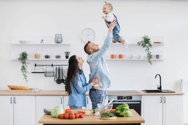 Yakışıklı, güçlü bir baba çocuğunu havada büyütürken bir yandan da heyecanlı bir anne kızını yemek odasında neşelendiriyor. Duygusal çift ve küçük kız evde yemek pişirirken mutluluğu ve eğlenceyi arttırıyorlar..