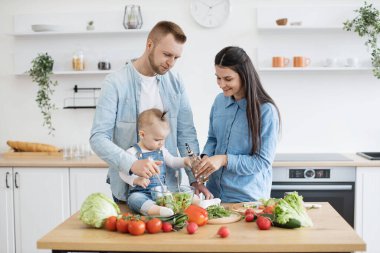 Kocası bileşenleri karıştırmaya yardım ederken dikkatli genç bir kadın kaseye zeytinyağı ekliyor. Sevecen üç kişilik aile leziz aperatiflerle aşçılık becerileri geliştiriyor..