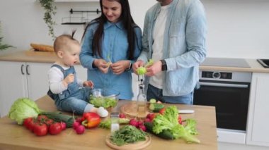 Kot giyen tatlı küçük kız elinde küçük bir dilim kırmızı sebze taşırken ilgili anne yeni ürünü tarif ediyor. Anne ve kızı sert yiyeceklerin dokusunu ve rengini daha iyi öğreniyorlar..