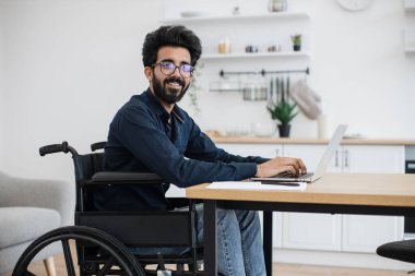 Uzak bir iş yerinde kalırken tekerlekli sandalyedeki gülümseyen kullanıcının taşınabilir bilgisayarda yazmasını kapat. Evden tam zamanlı iş yaparken neşeli profesyonel iş projesi..