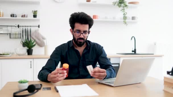 Арабський Молодий Чоловік Дивиться Контейнери Медикаментів Шукаючи Інформацію Екрані Ноутбука — стокове відео