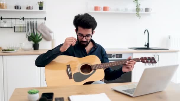Талантливый Индийский Музыкант Держащий Акустическую Гитару Анализируя Информацию Экране Ноутбука — стоковое видео