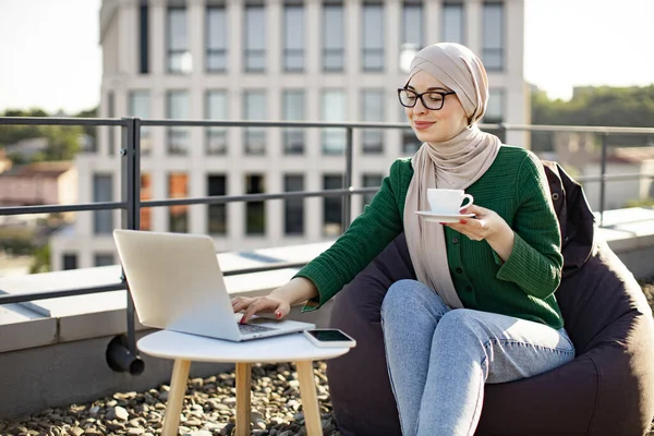 Portré Fiatal Hidzsáb Iszik Kávét Miközben Laptop Kis Asztalra Közel — Stock Fotó