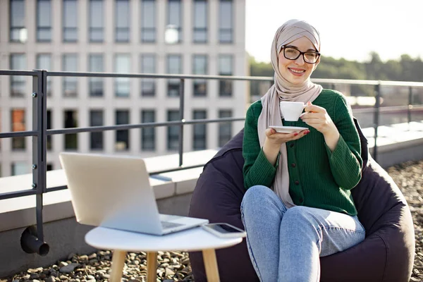 Portré Fiatal Hidzsáb Iszik Kávét Miközben Laptop Kis Asztalra Közel — Stock Fotó