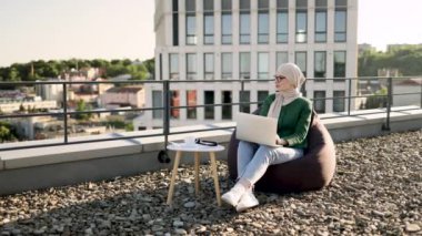 Güzel bir kadın gözlük takıyor ve dizüstü bilgisayarını açık koltukta dizlerinin üstünde tutarken hayal kuruyor. Güneşli bir günde ofis terasında kalırken yeni projeyi analiz eden Arap serbest yazar.