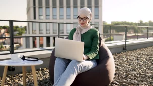 Femeie Musulmană Încântată Văl Uitându Cameră Timp Odihnește Gadget Inteligent — Videoclip de stoc
