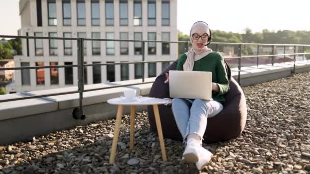 Сосредоточенная Арабская Женщина Хиджабе Наушниках Проводит Онлайн Конференцию Портативным Компьютером — стоковое видео
