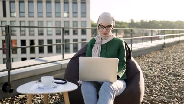 Hermosa Mujer Con Gafas Hijab Soñando Despierto Mientras Sostiene Ordenador — Vídeo de stock