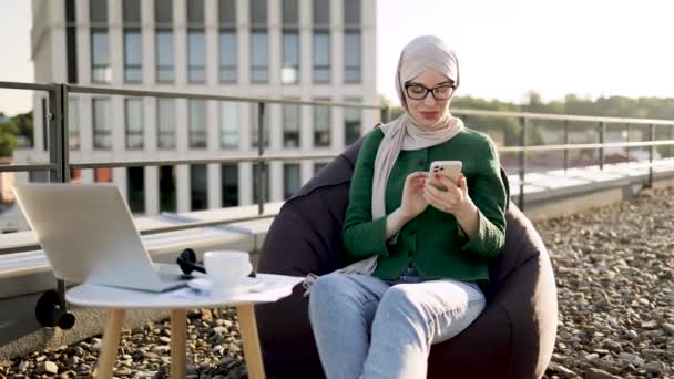 Mulher Muçulmana Alegre Que Está Envolvida Conversa Telefônica Enquanto Desenrola — Vídeo de Stock
