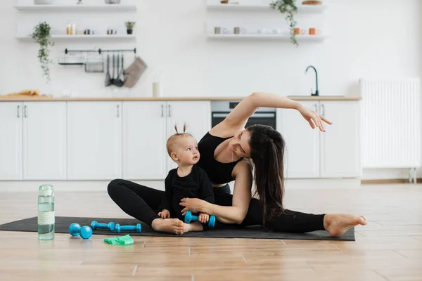 Young happy mother working out, doing butt bridge exercise