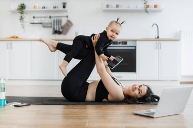 Bebek yogası yaparken kucuk kiz kucuk kizla kucuk kucuk kucuk kucuk kucuk kucuk kucuk poz veren mutlu bir kadin. Sağlıklı anne, evden ayrılmadan kız ve ebeveyn arasında bağ kurulmasını teşvik ediyor..