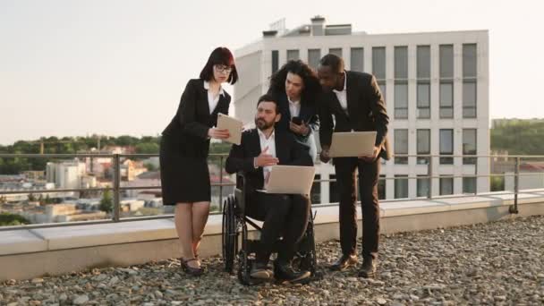 多种族全球专家在办公大楼的全景阳台上进行合作 并就新的建筑计划达成一致 白人残疾人看着数字平板电脑和手势手势 — 图库视频影像
