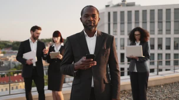 Портрет Успешного Африканского Предпринимателя Держащего Руках Мобильный Телефон Улыбающегося Камеру — стоковое видео