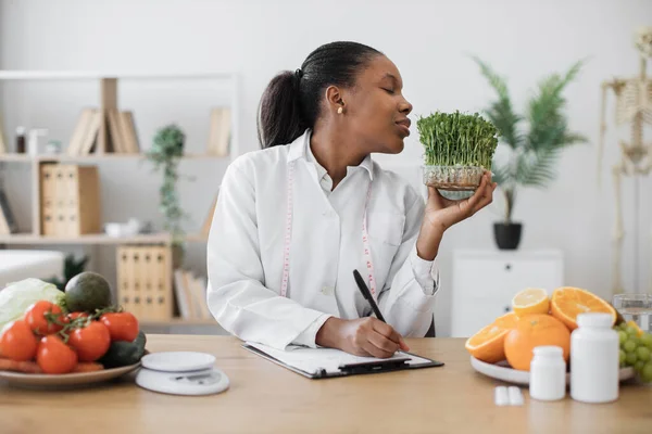 栄養士の仕事の日の間にプラスチック製の箱の野菜の苗の葉を検査する多人種の女性を確信しています 食品の医療専門家は マイクログリーンを介して健康支援コンポーネントを取得 — ストック写真