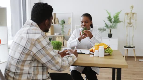 Afro Amerikaanse Diëtist Witte Jas Zetten Verse Avocado Voedingsschaal Tijdens — Stockvideo