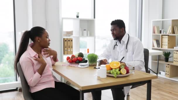 在与在职的多种族女人交谈时 有自信的男人 带着听诊器在剪贴板上写字 严重营养专家记录病人病史 以制定适当的膳食计划 — 图库视频影像
