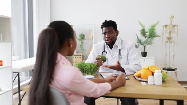 Konsültasyon Odasında Kadın Müşteriyle Konuşurken Elinde Avokado Tutan Beyaz Önlüklü — Stok video