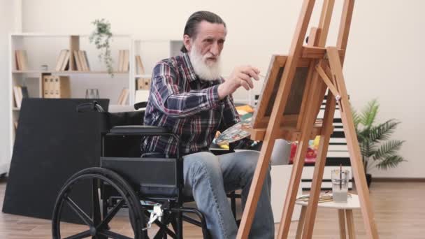 Γκρι Γενειοφόρος Συνταξιούχος Αναπηρία Κάθεται Μπροστά Από Ξύλινο Καβαλέτο Και — Αρχείο Βίντεο