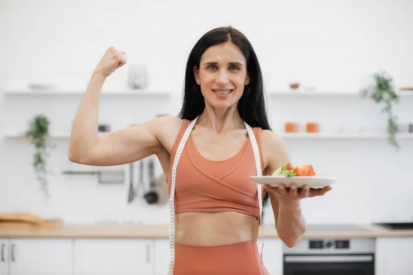 Piękna Sportowa Kobieta Pokazuje Mięśnie Ramienia Stojąc Jasnej Modnej Kuchni — Zdjęcie stockowe