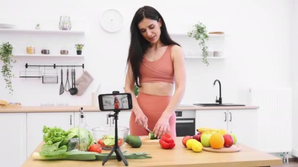 Χαμογελαστό Θηλυκό Activewear Προετοιμασία Γεύμα Από Φρέσκα Λαχανικά Κάμερα Κινητό — Αρχείο Βίντεο