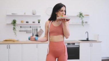 Spor elbiseli rahat bir kadının portresi. Elinde beslenme çanağı ve halterli ev yapımı halterler var. İyi beslenme ve zindelik vasıtasıyla yaşam tarzını değiştiren mezuralı mutlu sporcu.