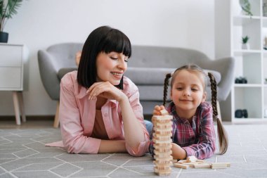 Güzel bir bayan, sıradan kıyafetler içinde, kule duvarına ahşap tuğla dizerken sevimli bir çocuk, annesinin başarısını seyrediyor. Yapı bloklarını değiştirirken sabırlı olmanın düşünceli ebeveyn öğretim önemi.