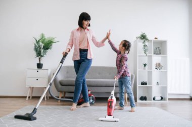 Dost canlısı bir kadın ve ergen bir çocuk, ellerinde elektrikli süpürgelerle birbirlerine beşlik çakıyorlar. Aile üyeleri ev idaresi görevlerinin başarısını işbirliği egzersizleri yoluyla kutluyorlar.