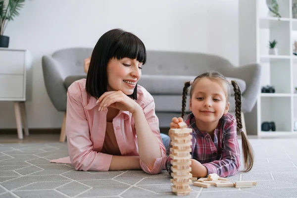Güzel bir bayan, sıradan kıyafetler içinde, kule duvarına ahşap tuğla dizerken sevimli bir çocuk, annesinin başarısını seyrediyor. Yapı bloklarını değiştirirken sabırlı olmanın düşünceli ebeveyn öğretim önemi.