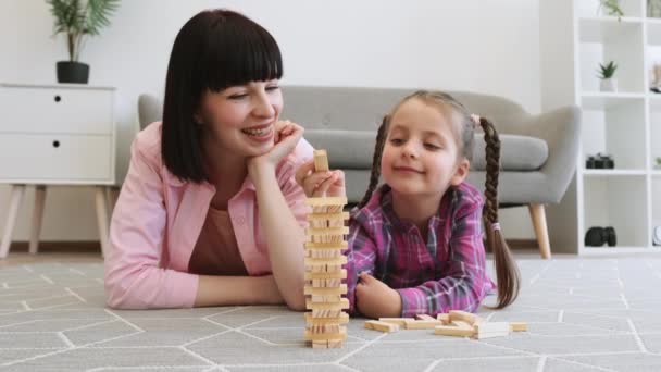 Lächelnde Familienfrau Mit Hölzernen Ziegelsteinen Spielt Strategiespiel Mit Zwillingsmädchen Auf — Stockvideo