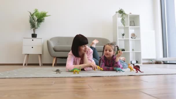 近距离观察多情的母亲和好奇的孩子在客厅里玩塑料玩具恐龙游戏 有爱心的女性父母通过建立自己的想象世界激发女儿的创造力 — 图库视频影像