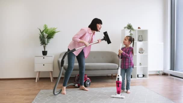 Excited Mother Using Vacuum Cleaner Imaginary Guitar While Daughter Pretending — Stock Video