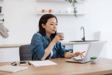 Güzel bayan kahve aşığı mutfakta çalışırken en sevdiği içkiyi içiyor. Yorgun Asyalı bir kadın uzun süreli çalışmadan sonra internete kablosuz bilgisayarla girip çıkıyor..