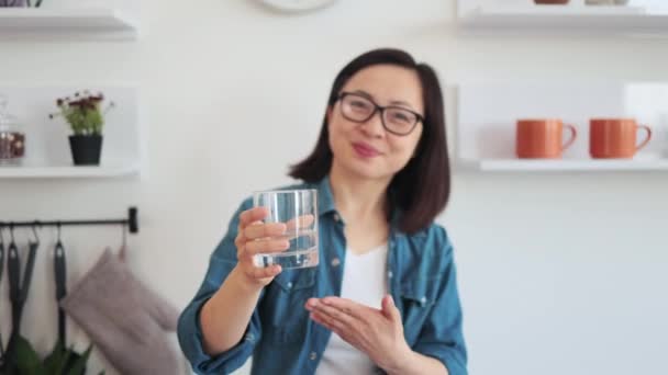 デニムシャツのスリムな女性の喜びの選択的な焦点と手の飲料に注意を引く光景 美しいアジアの女性は体の健康のための利点のためにぬるま湯を推薦します — ストック動画