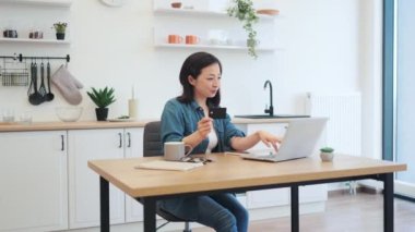 Banka kartı olan bir kadın bilgisayarın arkasında evet işareti gösteriyor