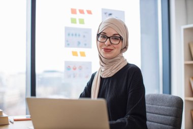 Geleneksel türbanlı çekici Müslüman bayanın yaratıcı iş yerinde çalışma saatlerini yakın çekimde geçirmesi. Profesyonel işveren iş yönetirken taşınabilir aygıt üzerinde çeşitli görevler yerine getiriyor.