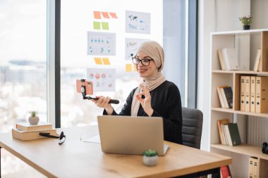Güzel müslüman kadın, akıllı telefonlu selfie çubuğu ile video içeriğini kaydediyor.